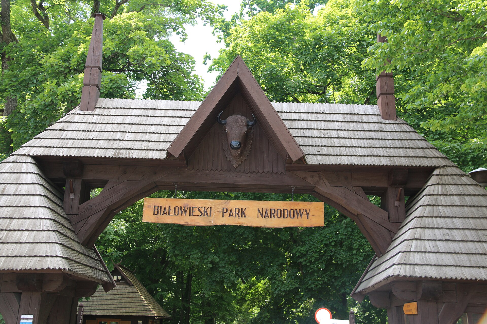 Porte en bois de l'entrée du parc national de Białowieża, surmontée d'une tête de bison sculptée