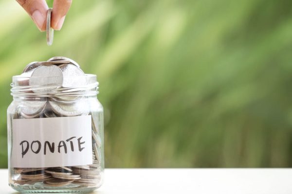 hand-putting-coins-in-glass-jar-for-giving-and-donation-concept-picture-id813128966